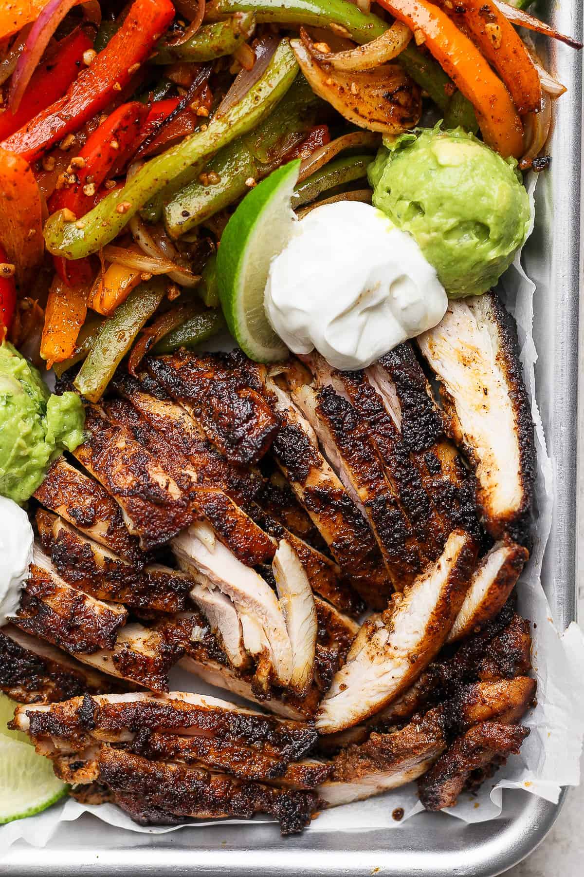 Fully cooked chicken fajitas on a large baking sheet.