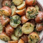 Close up shot of a bowl of boiled potatoes with herbs.