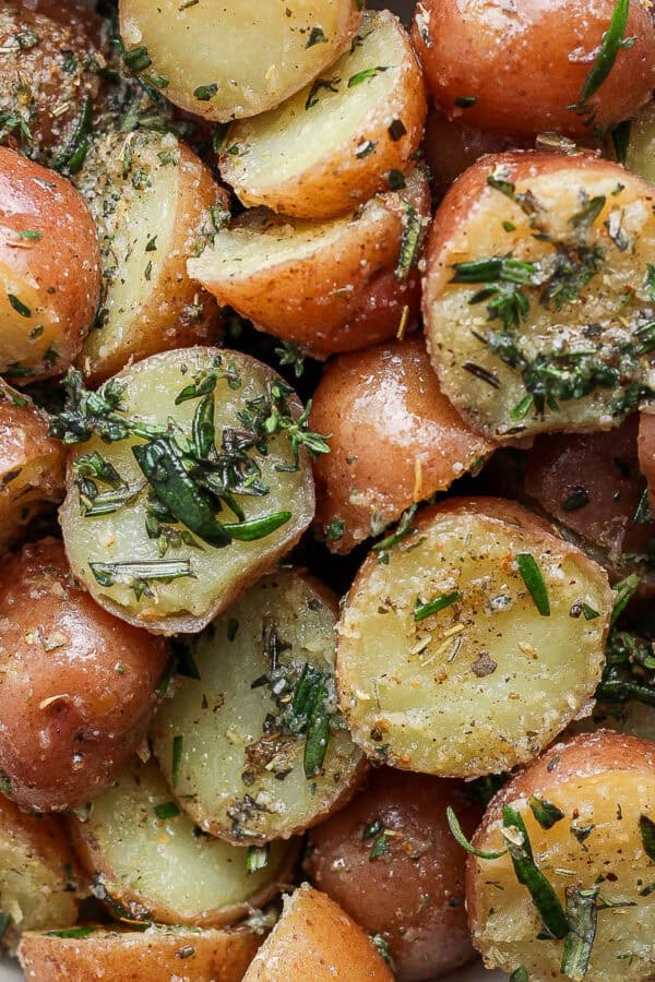 Close up shot of a bowl of boiled potatoes with herbs.