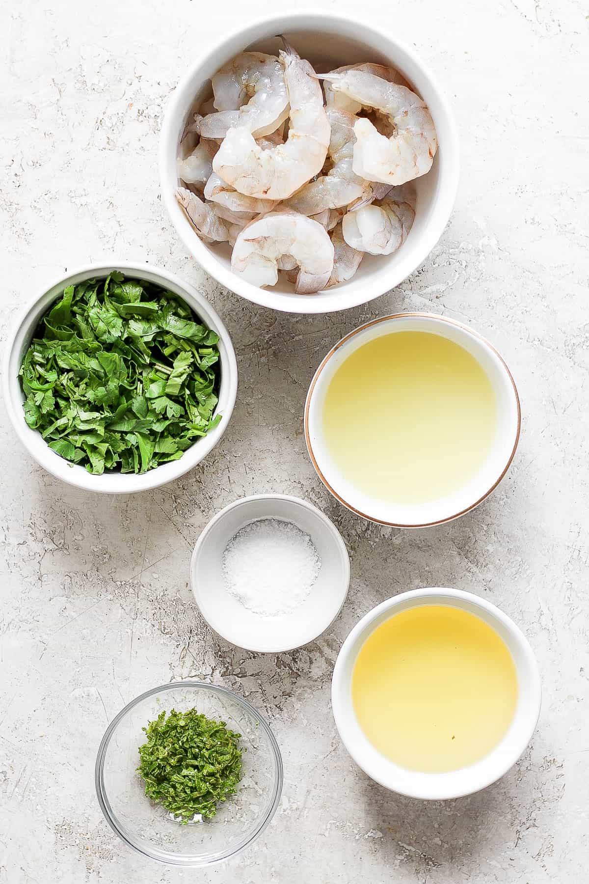 Raw shrimp and marinade ingredients in separate bowls.