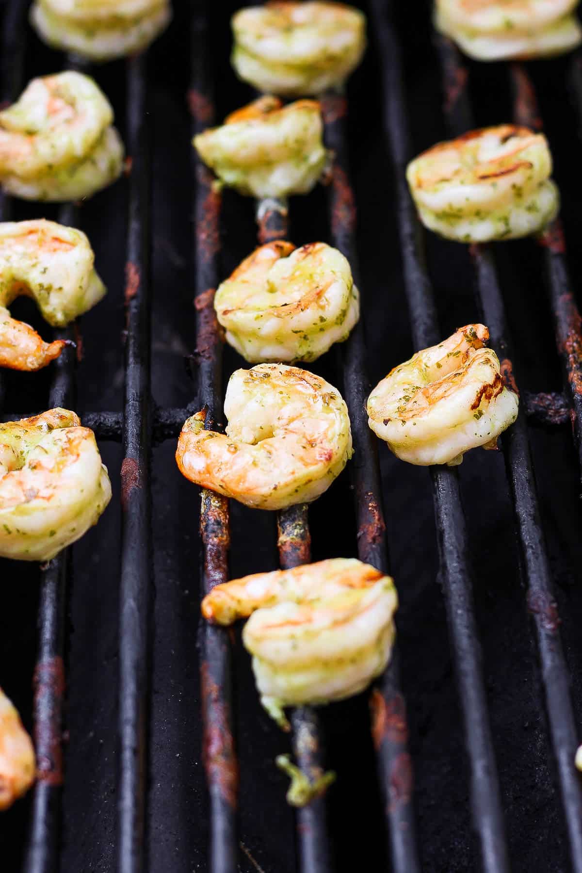 Marinated shrimp cooking on the grill grates.