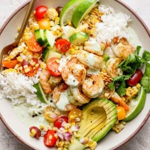 Top down shot of a bowl filled with rice, cilantro lime shrimp, grilled corn salad and avocado.