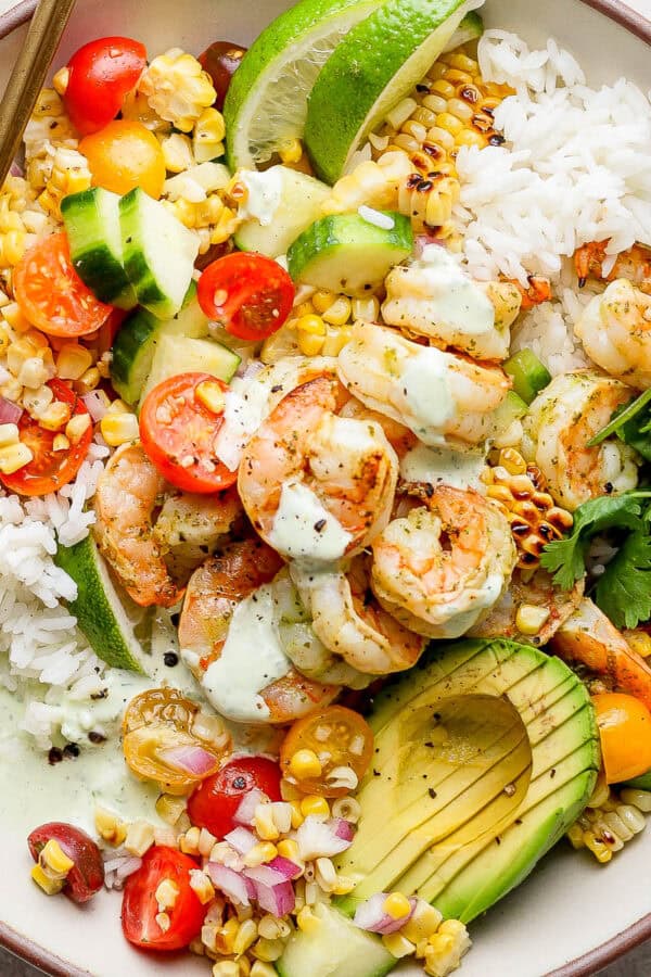Top down shot of a bowl filled with rice, cilantro lime shrimp, grilled corn salad and avocado.