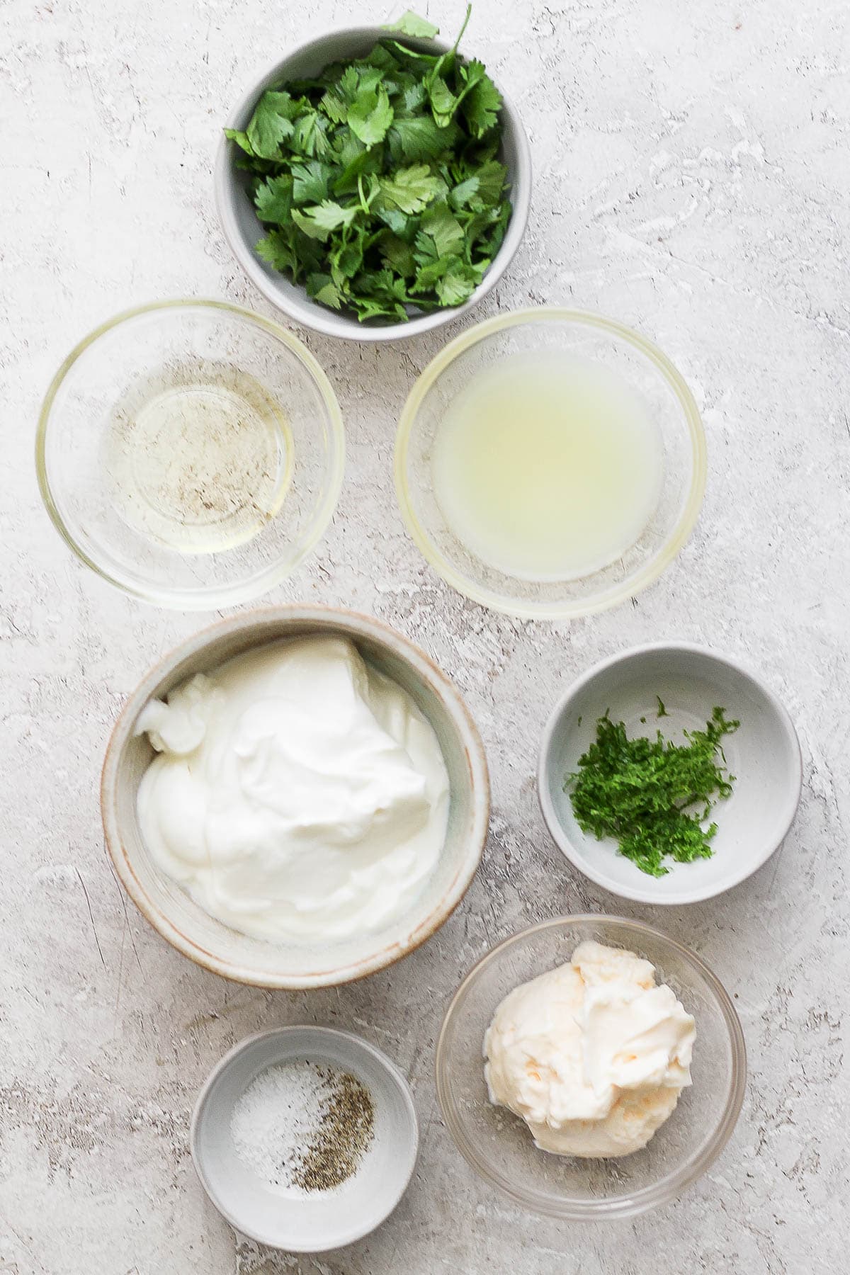 Ingredients for cilantro yogurt sauce in separate bowls.