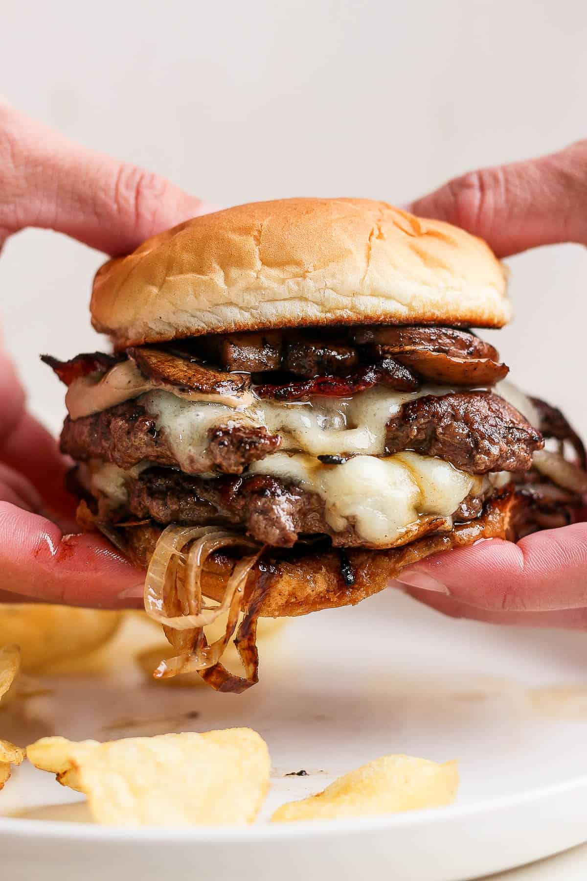 Two hands holding a mushroom swiss burger.