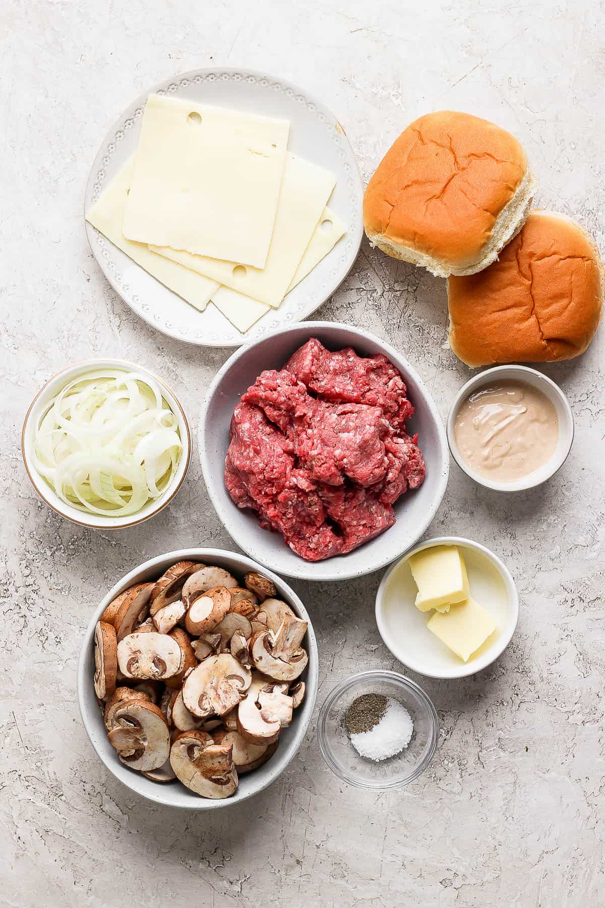 Pieces of the mushroom swiss burger on separate plates and bowls.