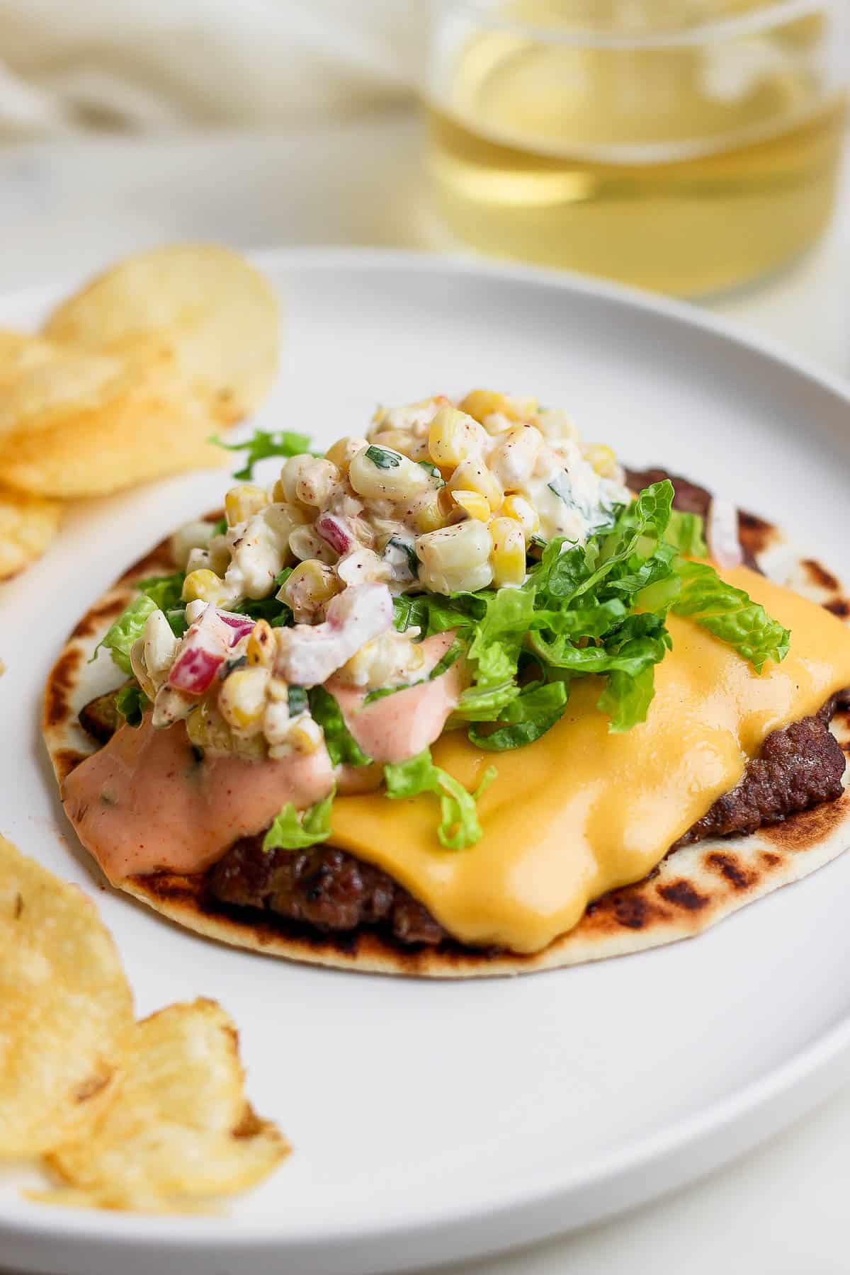 A smashed burger taco on a plate with toppings added on top.