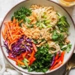 Top down shot of a big bowl of Thai Peanut Noodles with cilantro, carrots, onions, bell peppers and green onion.