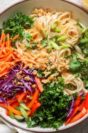 Top down shot of a big bowl of Thai Peanut Noodles with cilantro, carrots, onions, bell peppers and green onion.