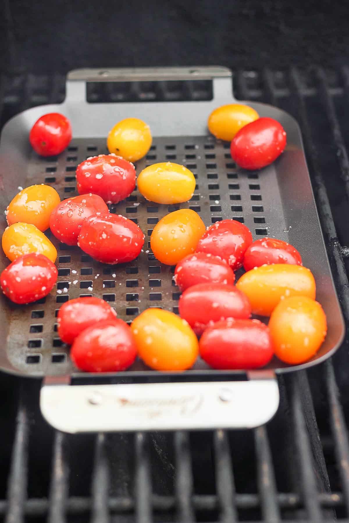 Cherry tomatoes in a small grill pan on the grill.