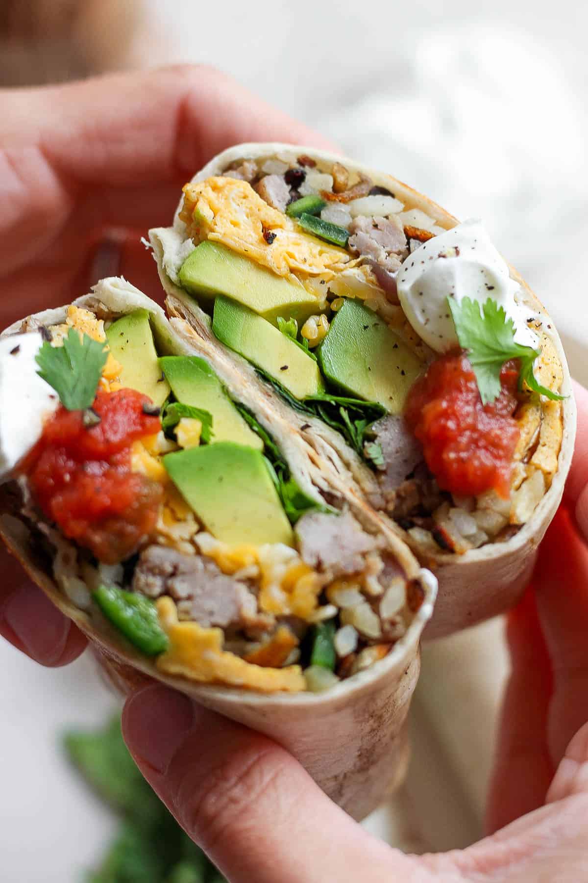 A breakfast burrito cut in half and toppings added.