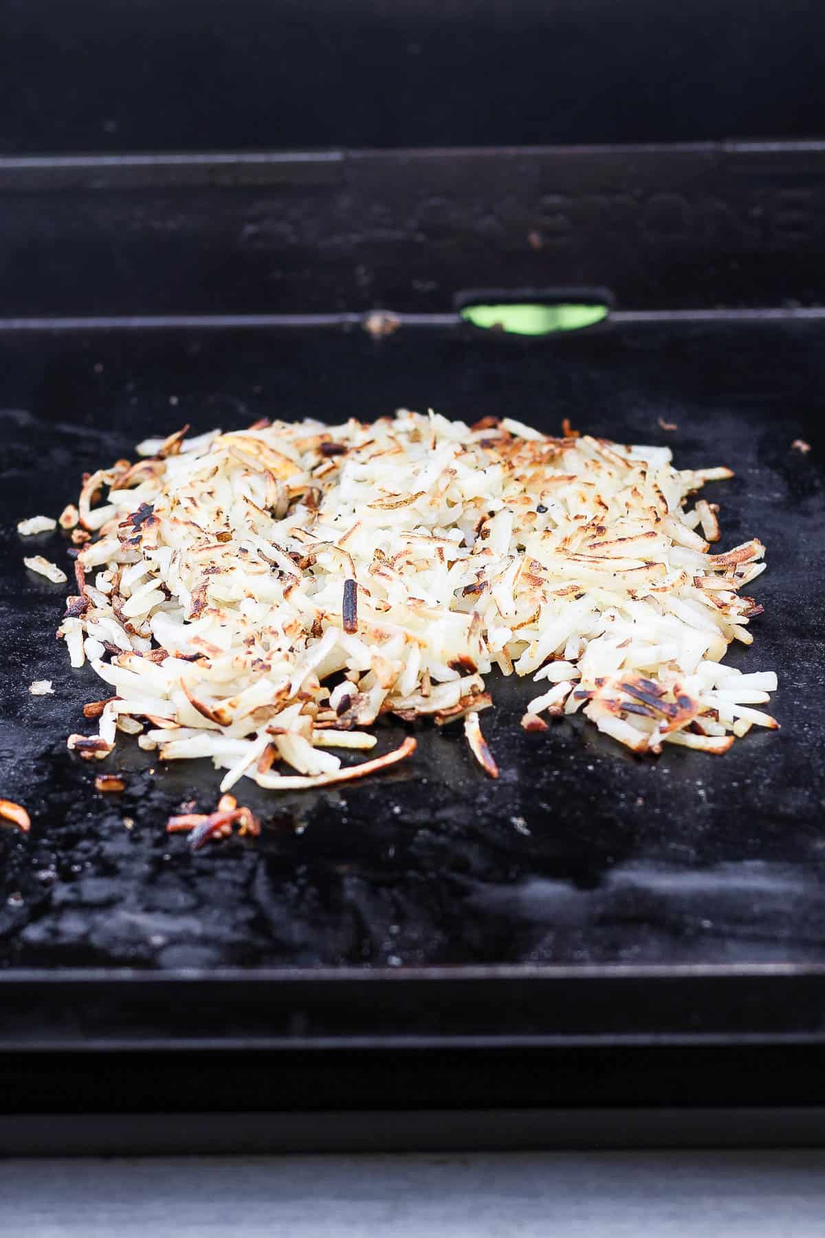 Hash browns cooking on the griddle.