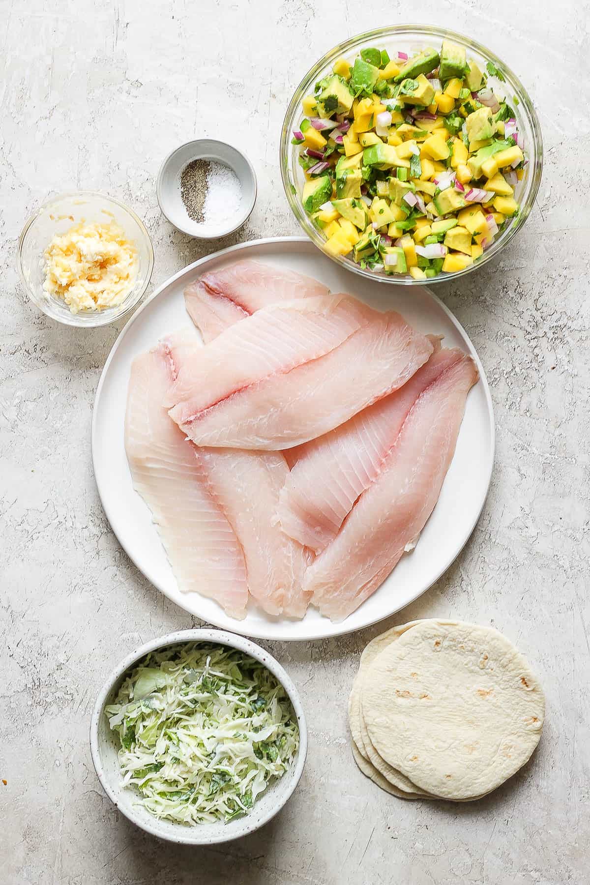 Ingredients for grilled fish tacos in separate bowls.