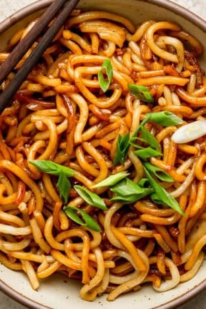 Bowl of Hibachi Noodles in a bowl with two chopsticks on the side and some sliced green onions on top.