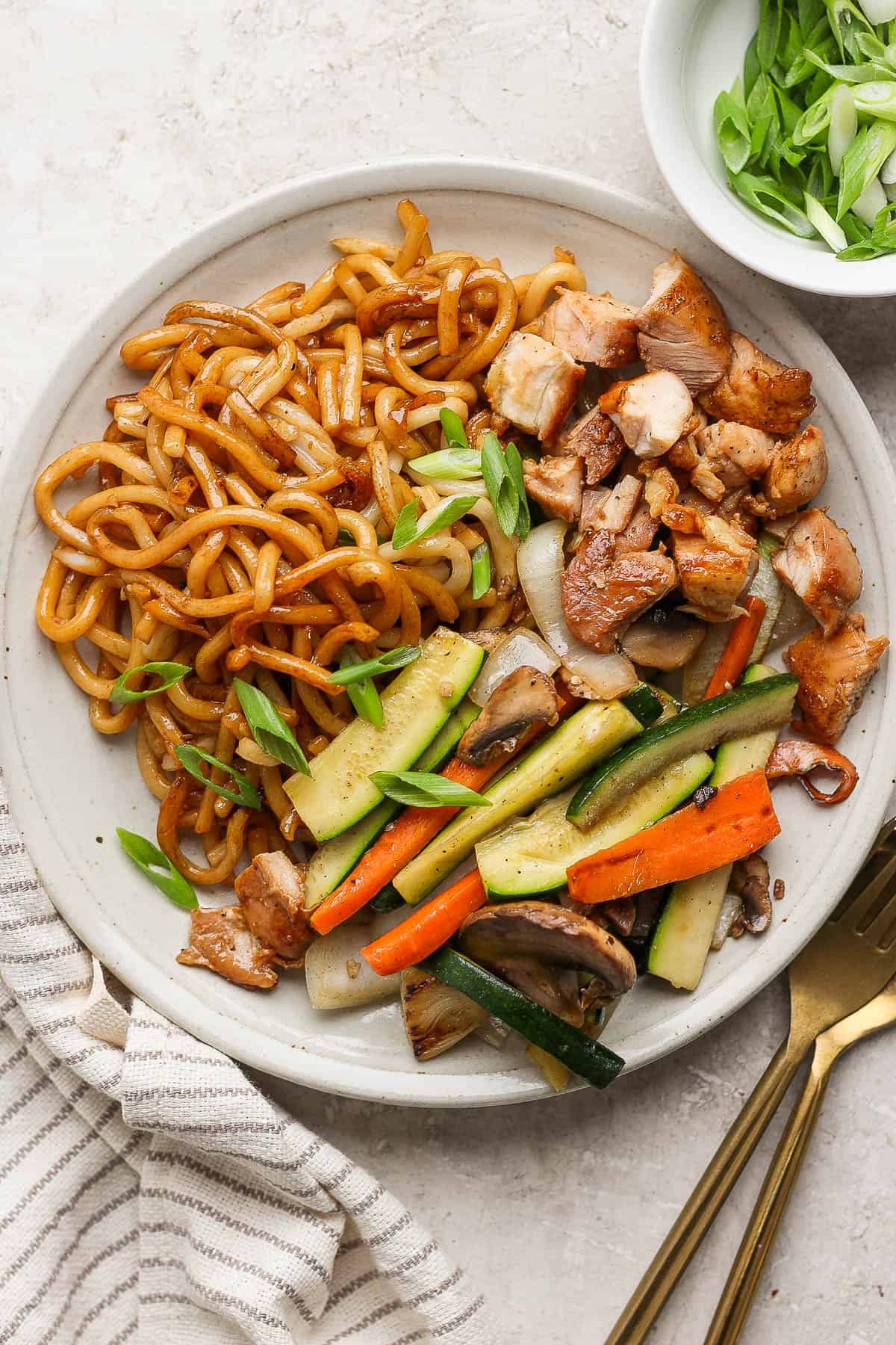 Hibachi noodles on a plate with vegetables and chicken.