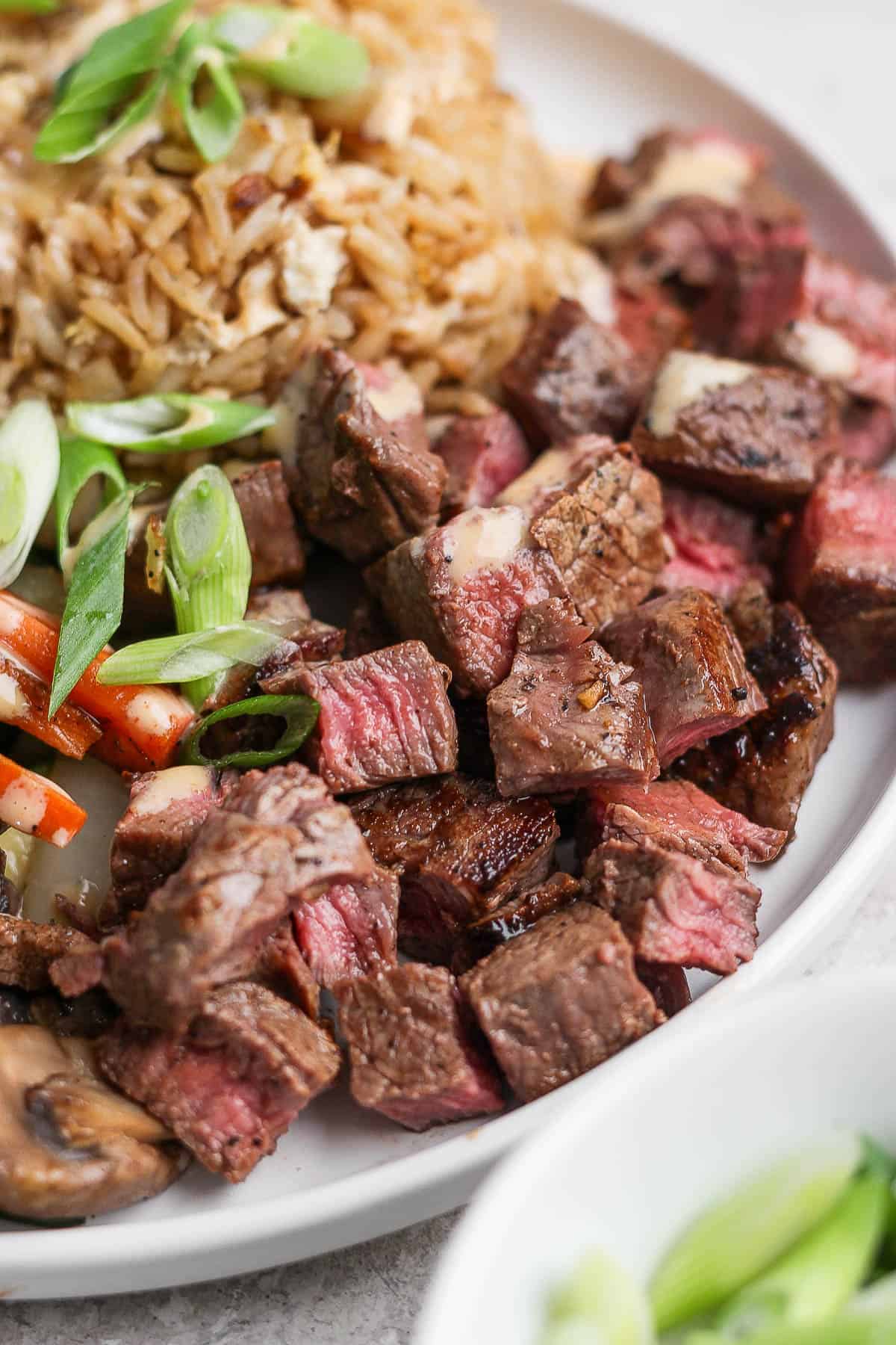 Hibachi steak on a plate with yum yum sauce on top.