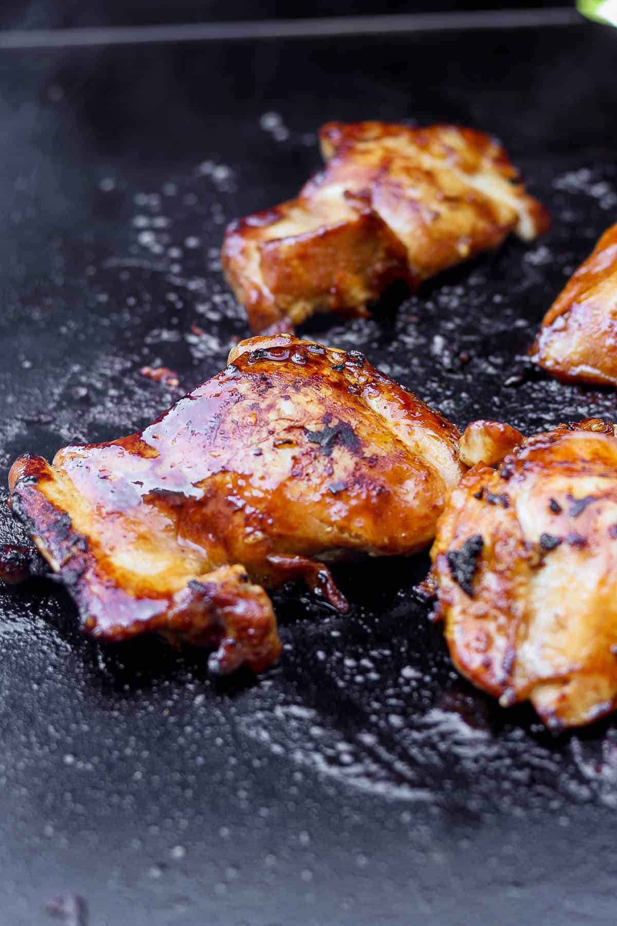 Marinated chicken thighs cooking on a hot Blackstone griddle.