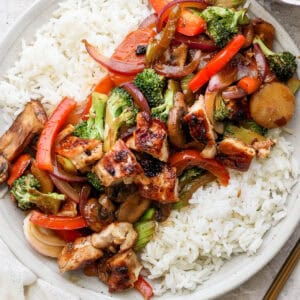 A shallow bowl full of cooked rice and topped with Blackstone stir fry with chicken.