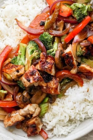 A shallow bowl full of cooked rice and topped with Blackstone stir fry with chicken.