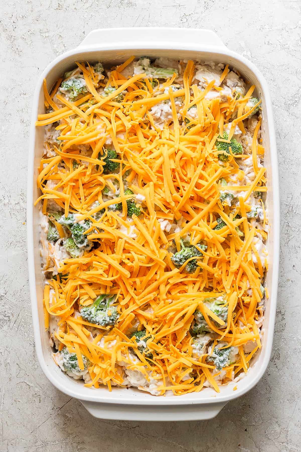 Shredded cheddar cheese topped on top of the mixture in the casserole dish.