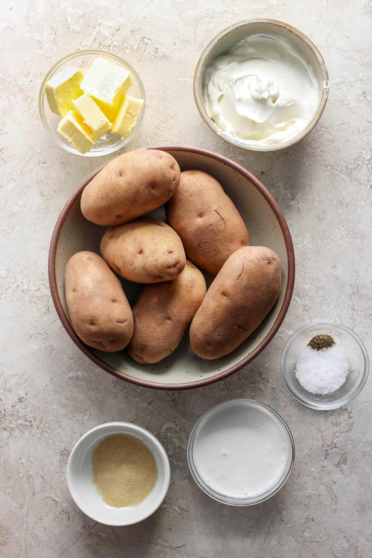 Ingredients for extra creamy mashed potatoes in separate bowls.