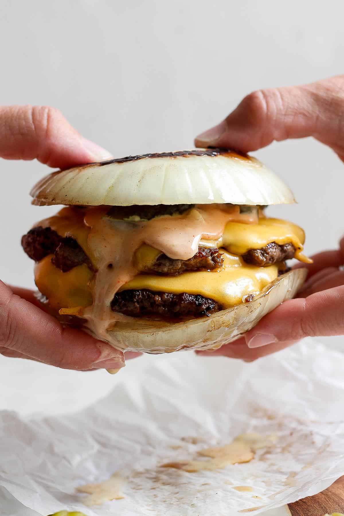 A fully assembled flying dutchman burger being held by two hands.