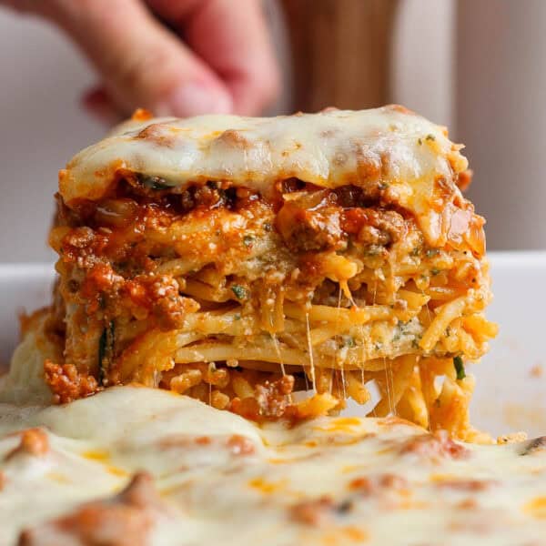 Someone pulling out a big piece of Million Dollar Spaghetti from a pan.