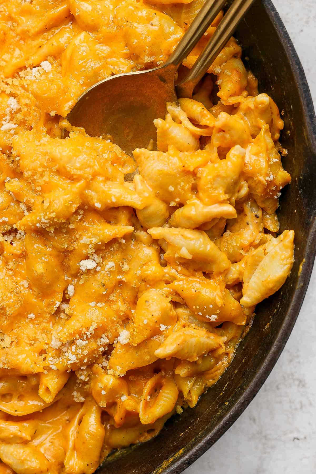 A close up of baked pumpkin mac and cheese in a cast iron skillet.