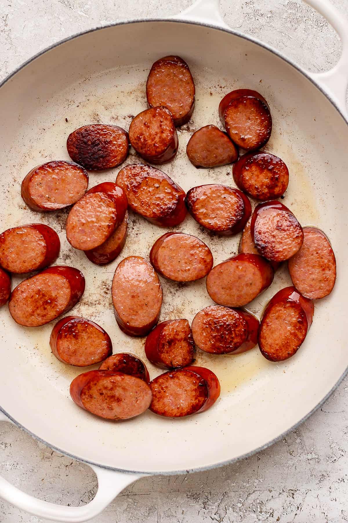 Sliced sausages in a dutch oven geting seared.