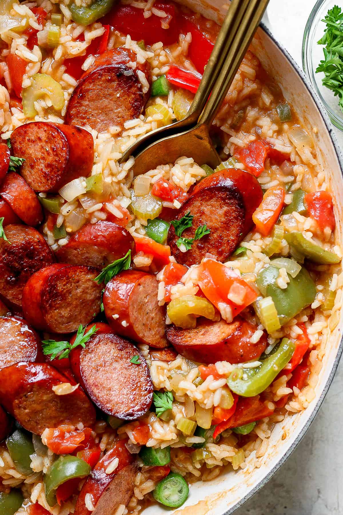 Sausage and rice in the dutch oven with two spoons.