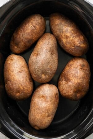 Top down shot of a slow cooker filled with baked potato.