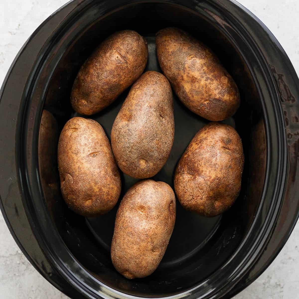 Top down shot of a slow cooker filled with baked potato.