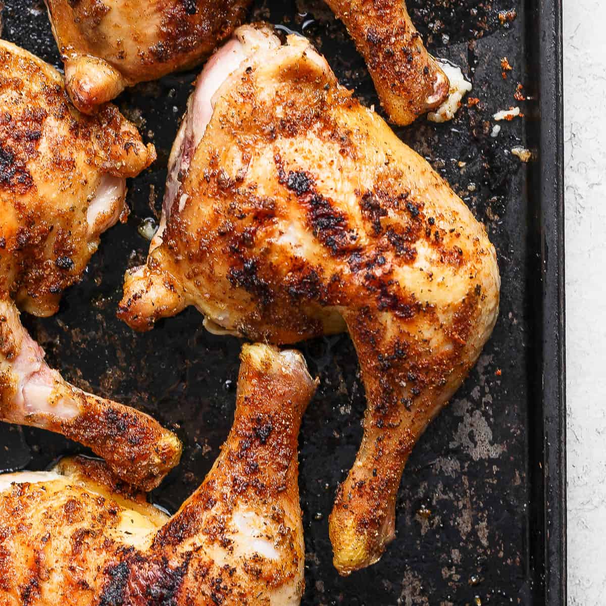 Top down shot of a smoked chicken quarter on a baking sheet.