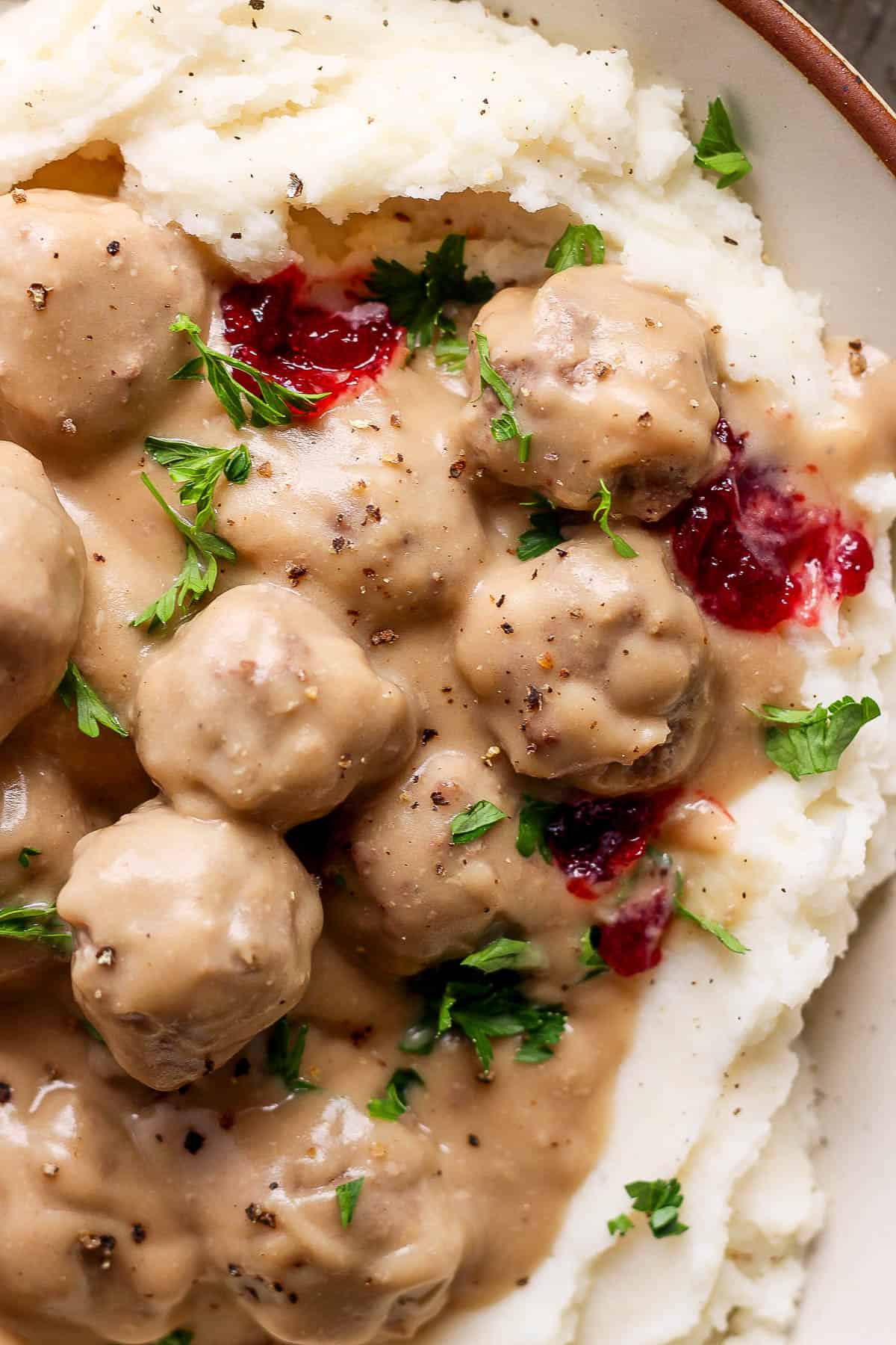 Close-up image of Swedish meatballs in a bowl of mashed potatoes.