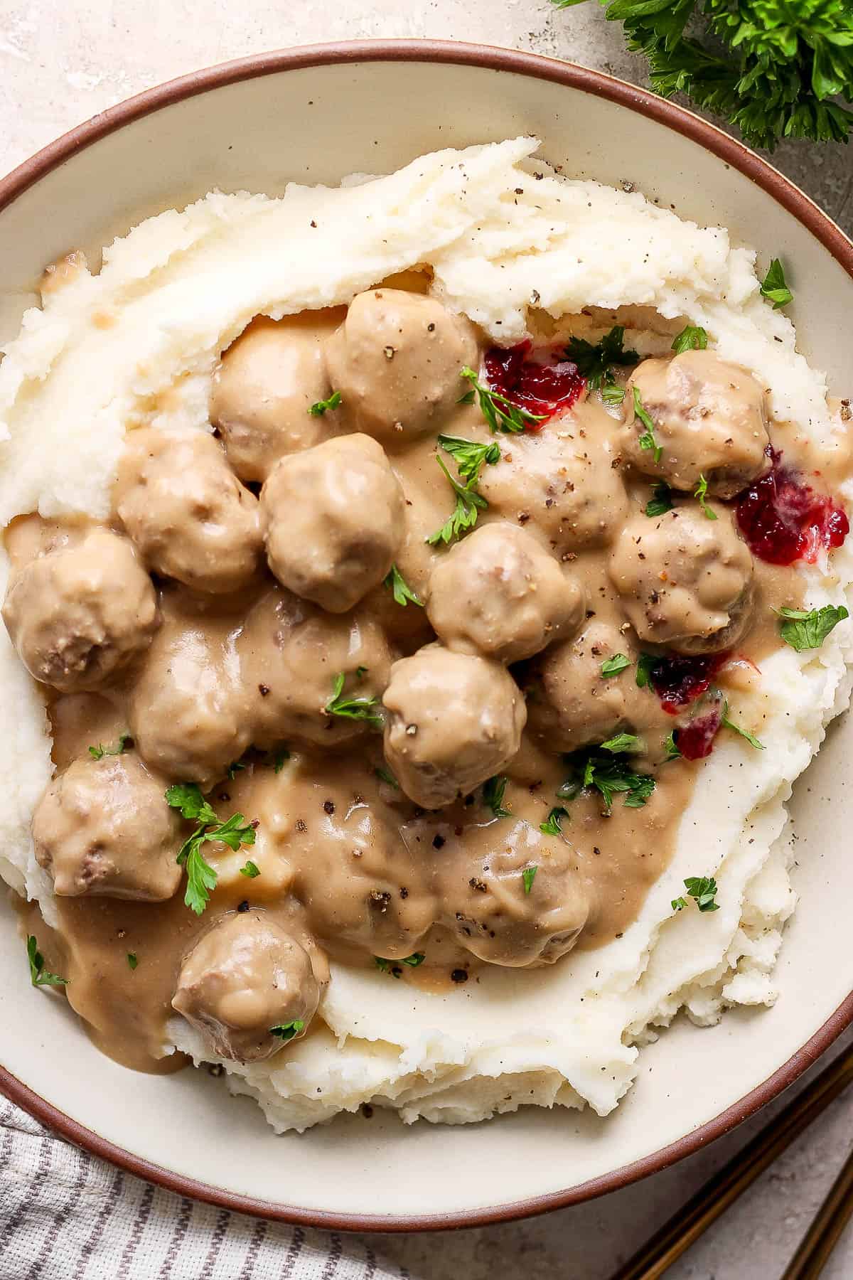 Swedish meatballs and gravy on top of mashed potatoes with a little bit of lingonberry jam and fresh parsley.