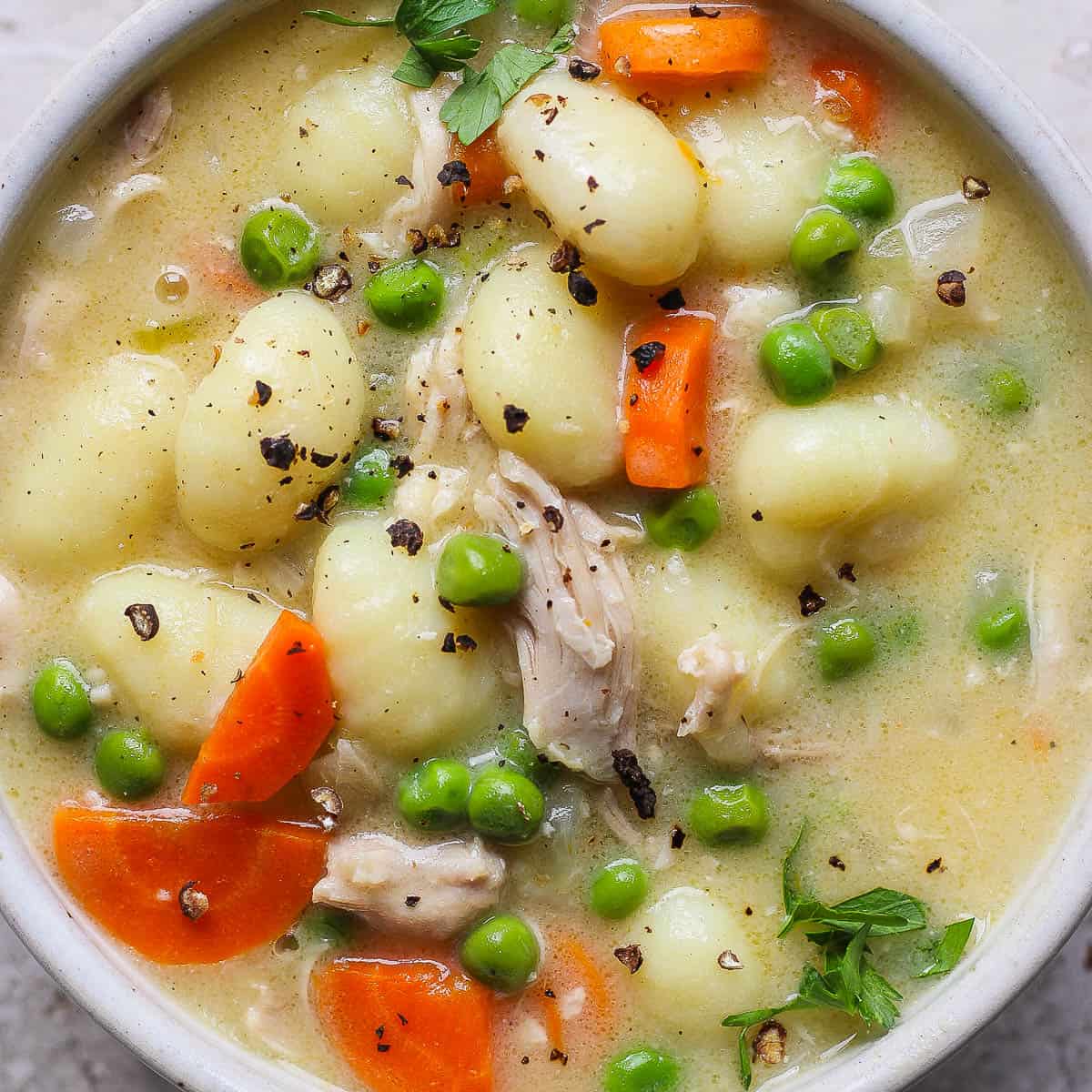 Bowl of chicken gnocchi soup with a spoon sticking out.