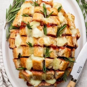 Top down shot of a cranberry brie pull apart loaf of bread cut into bite-sized pieces with rosemary.