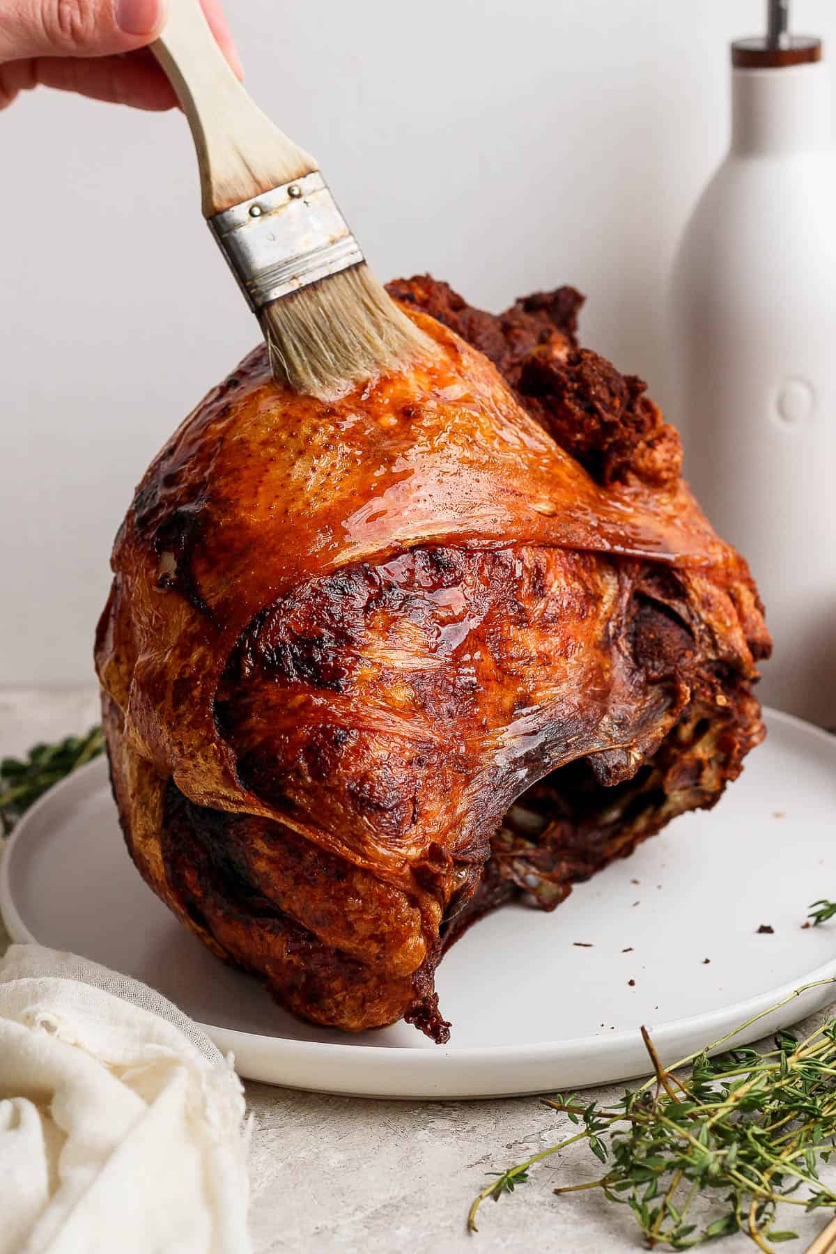 A deep fried turkey breast on a plate being brushed with butter.