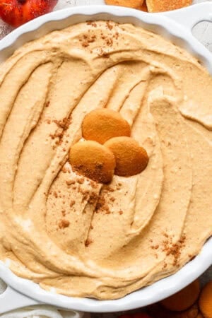 Homemade pumpkin pie dip in a pie plate with Nilla wafers sitting on top and a sprinkling of pumpkin pie spice.