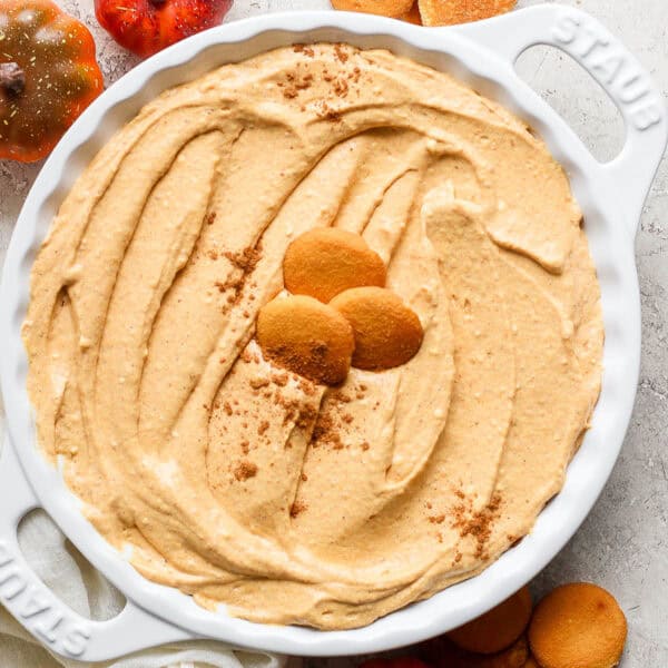 Homemade pumpkin pie dip in a pie plate with Nilla wafers sitting on top and a sprinkling of pumpkin pie spice.