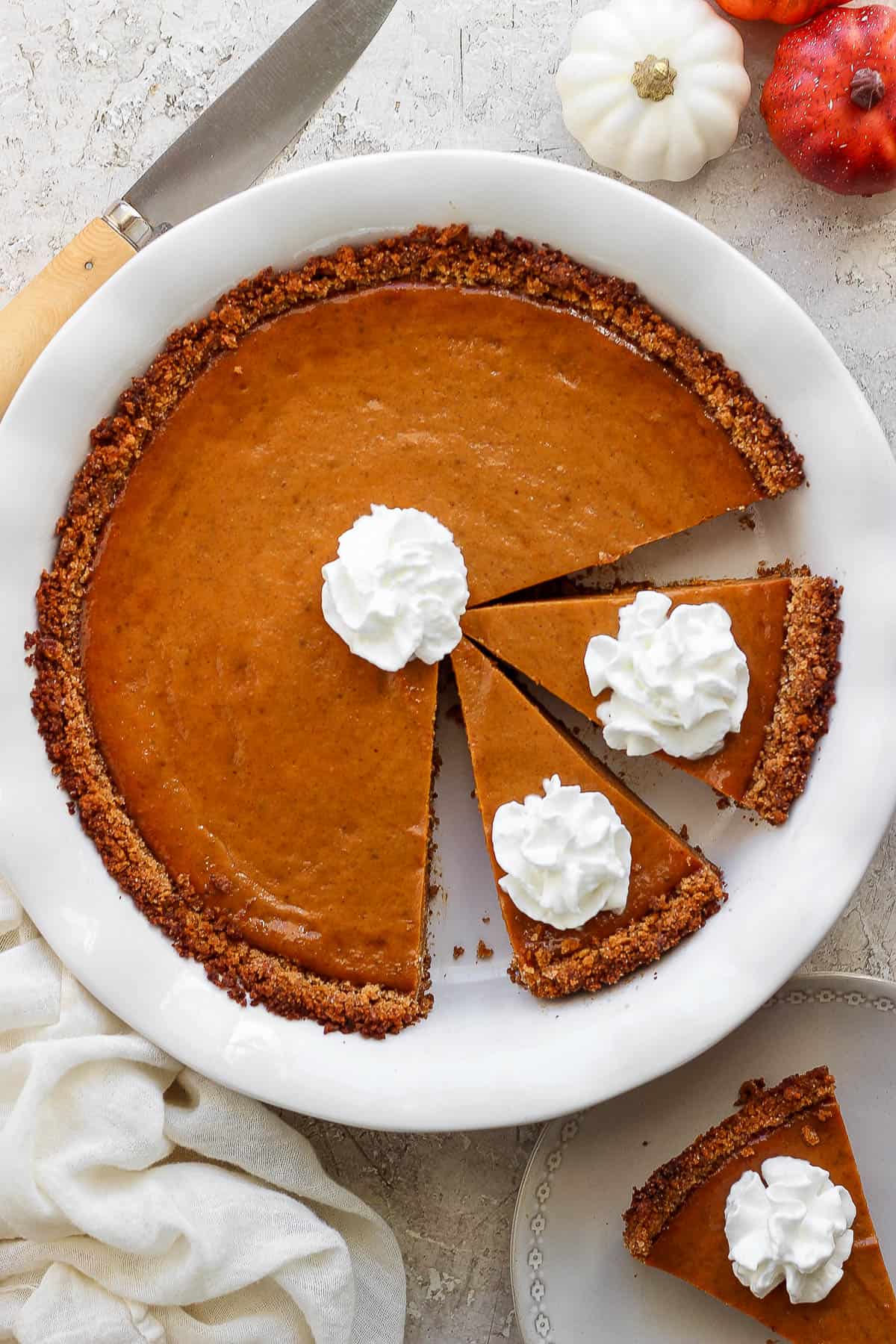 A fully baked pumpkin pie with whipped cream on top.