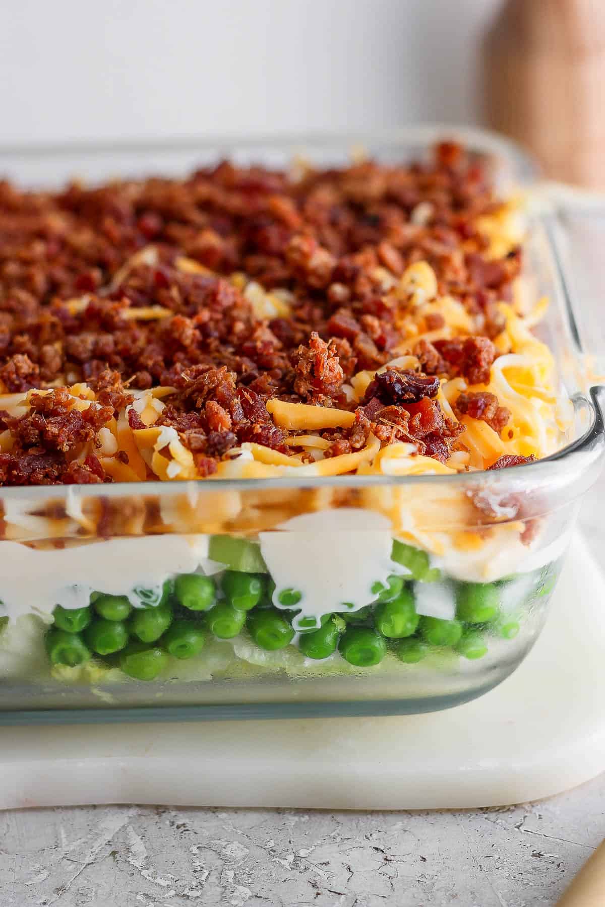 A fully layered seven layer salad in a glass baking dish.