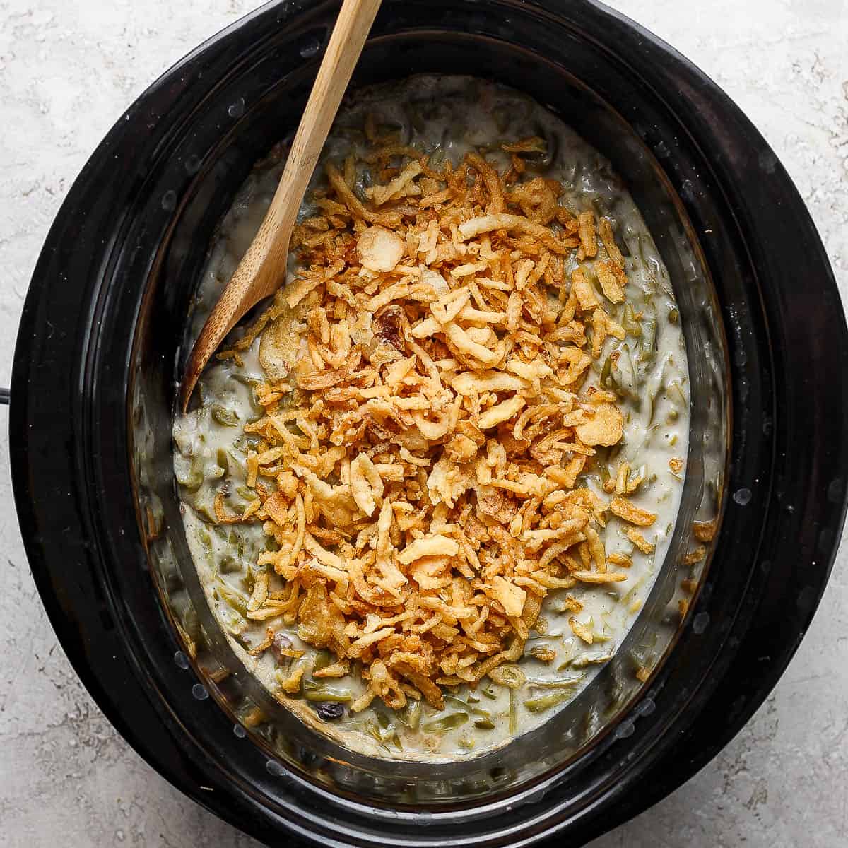 Top down shot of a slow cooker filled with green bean casserole.