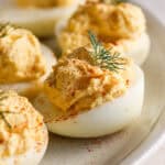 A side shot of a smoked deviled egg with paprika and dill garnish.