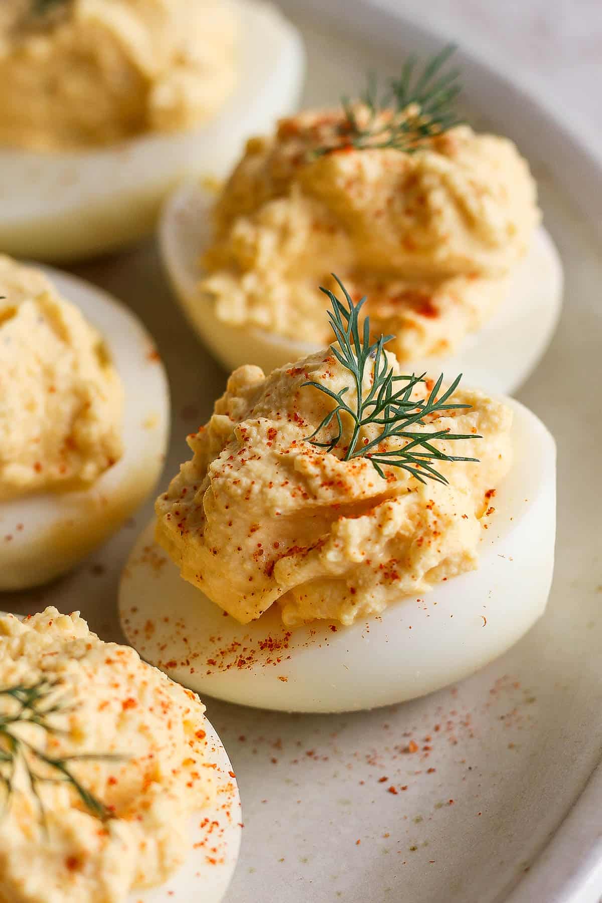 Deviled eggs on a plate garnished with paprika and dill.