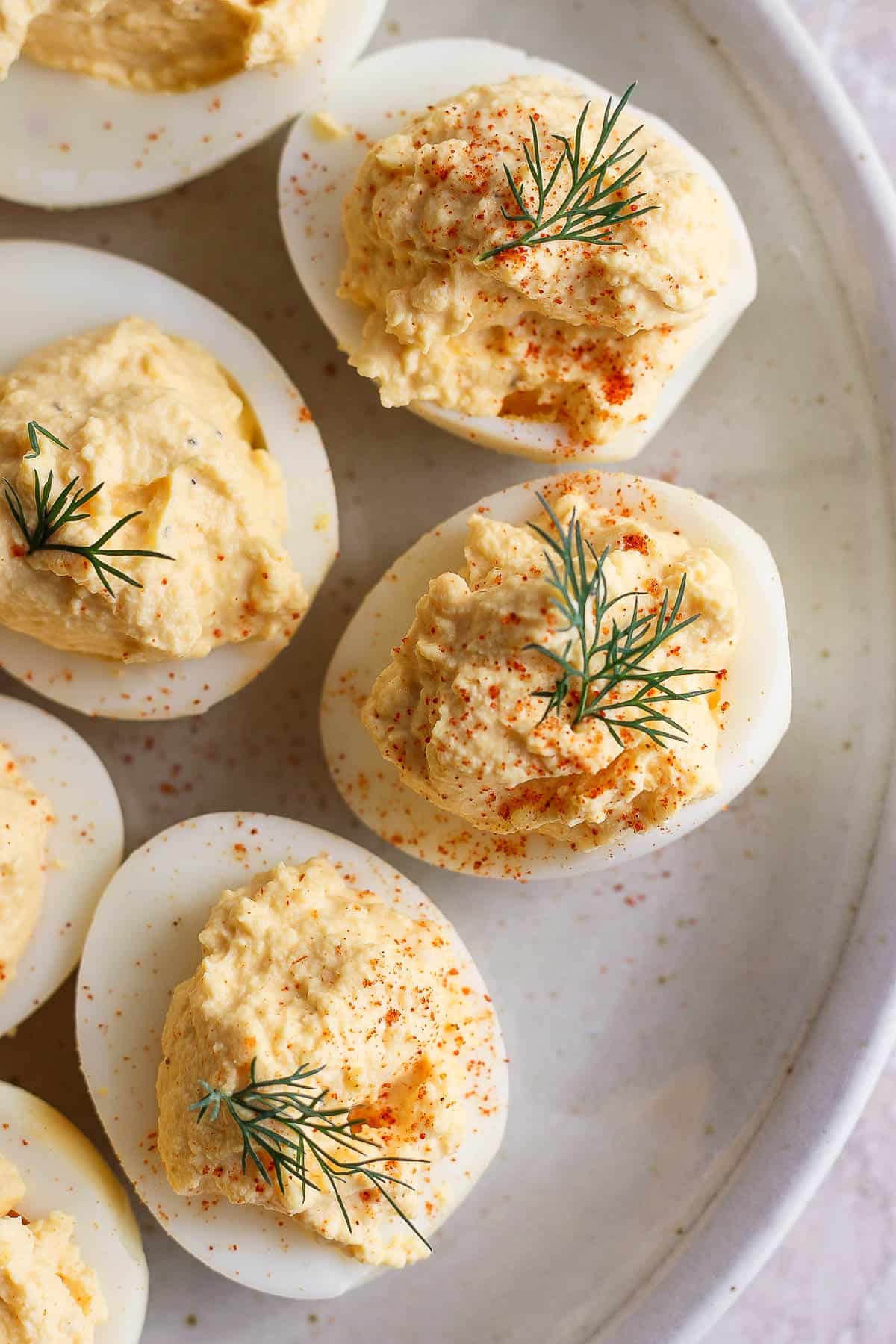 A plate full of garnished smoked deviled eggs.