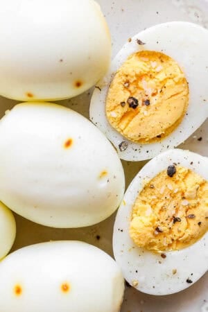 A top down shot of a plate of smoked eggs with one cut open to show the cooked inside with salt and pepper on top.