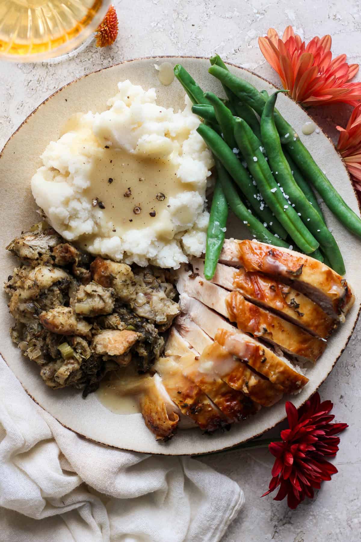 Crock pot stuffing on a plate with potatoes, turkey, green beans, and gravy.