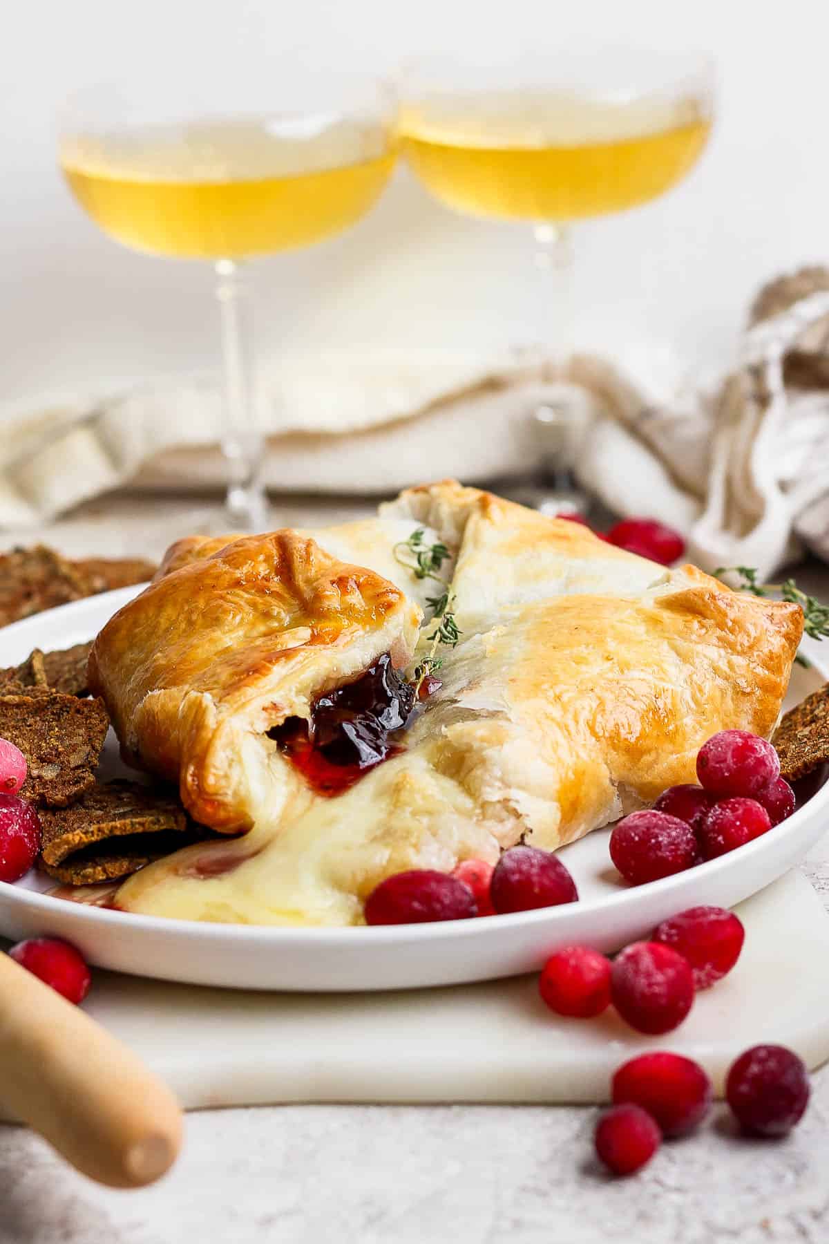 A fully baked puff pastry on a plate with fresh thyme and crostini crackers.