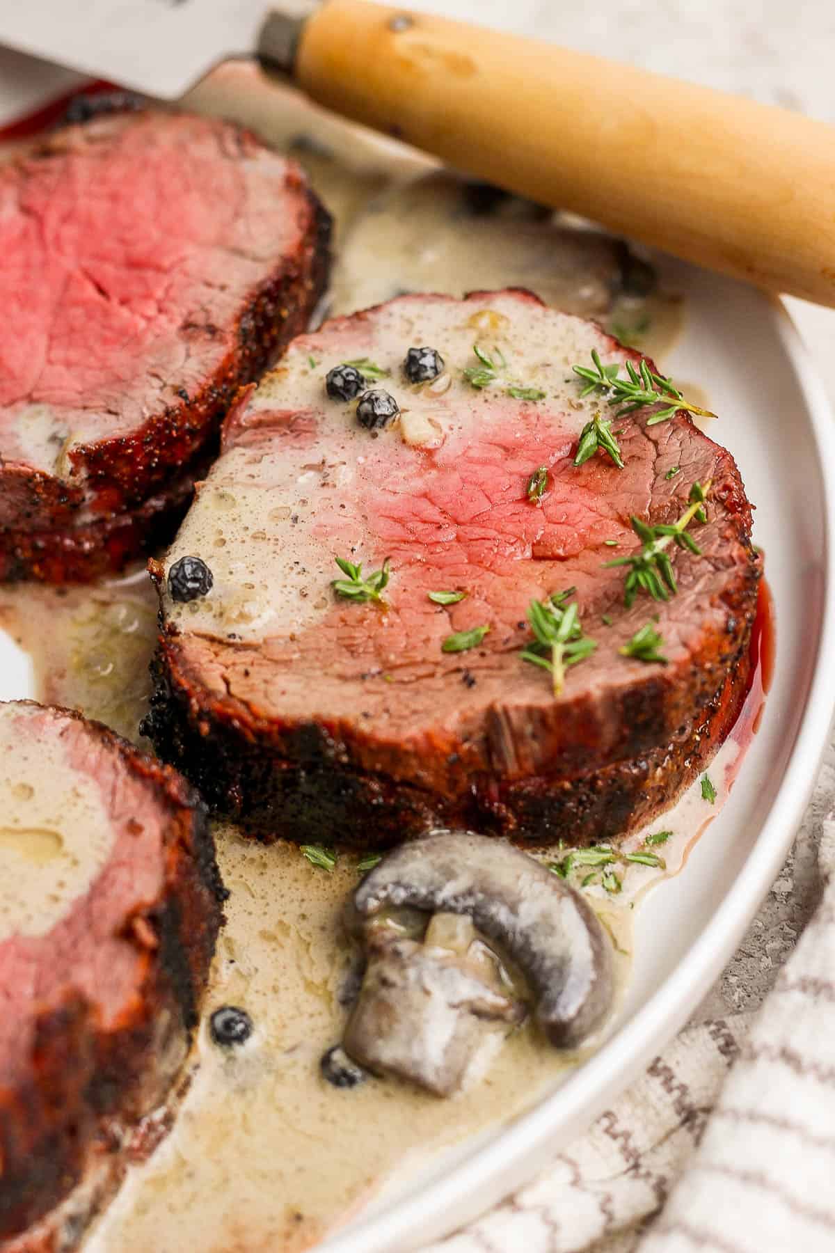 Beef tenderloin medallions on a white plate with the mushroom sauce on top.